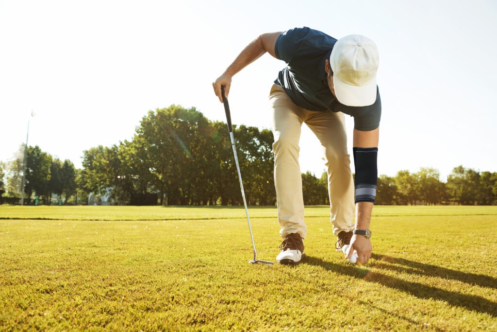 Young male golfer placing golf ball on a tee